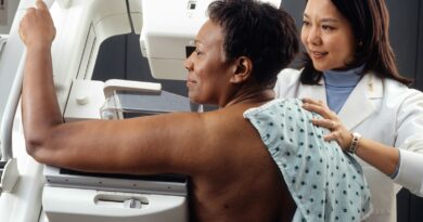 A radiographer helping a woman position for a mammogram