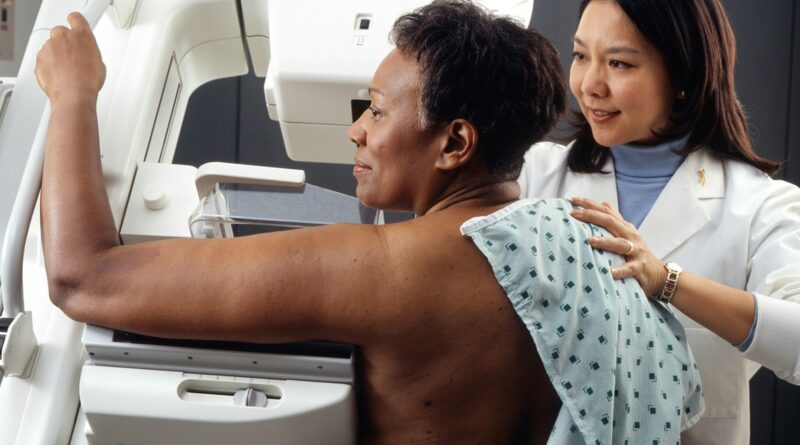 A radiographer helping a woman position for a mammogram