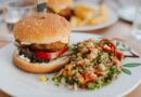 A burger served with a grain and vegetable salad on a plate