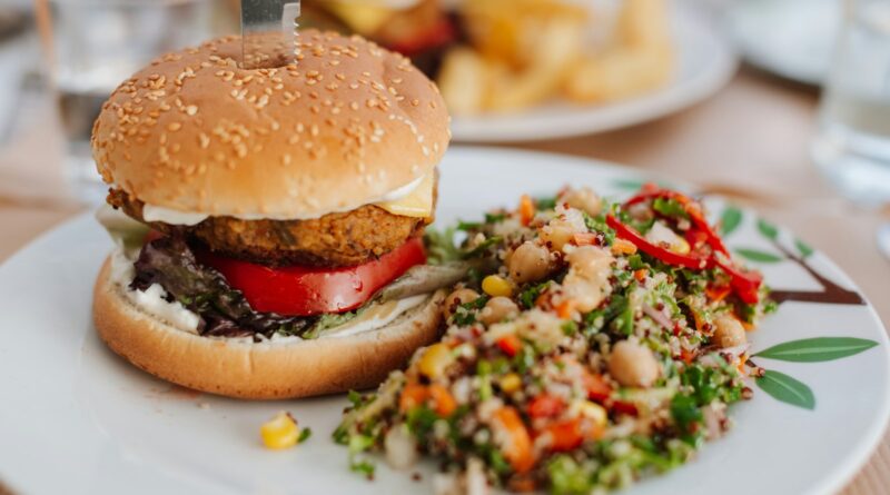 A burger served with a grain and vegetable salad on a plate
