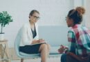A therapist taking notes while talking with a client in a bright consulting room