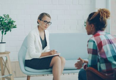 A therapist taking notes while talking with a client in a bright consulting room