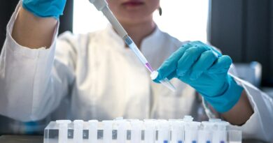 A researcher in blue gloves pipetting samples into test tubes in a laboratory