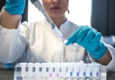 A researcher in blue gloves pipetting samples into test tubes in a laboratory